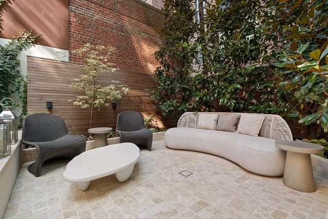 a view of a patio with couches and chairs under an umbrella
