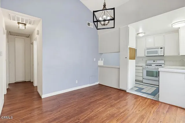 a view of a kitchen with wooden floor and electronic appliances