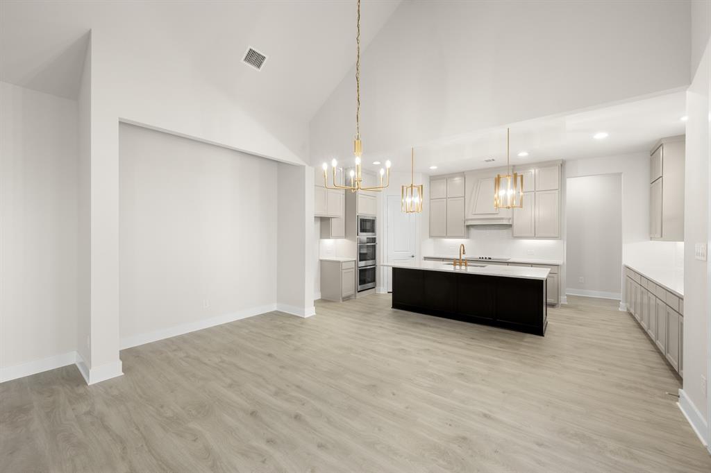 151 Talpin Lane Venus, TX 76084 - Photo 7 of 28 a large white kitchen with kitchen island a sink stainless steel appliances and a chandelier