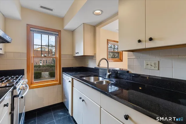 a kitchen with granite countertop a sink stove and cabinets