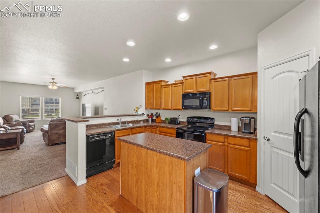 6310 Pilgrimage Road Colorado Springs, CO 80925 - Photo 12 of 31 a kitchen with stainless steel appliances granite countertop a stove top oven a sink dishwasher a refrigerator and cabinets with wooden floor