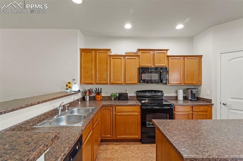 6310 Pilgrimage Road Colorado Springs, CO 80925 - Photo 13 of 31 a kitchen with kitchen island granite countertop a sink counter top space and stainless steel appliances