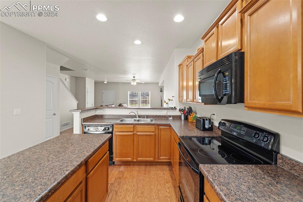 6310 Pilgrimage Road Colorado Springs, CO 80925 - Photo 14 of 31 a kitchen with stainless steel appliances granite countertop a stove a sink and a microwave
