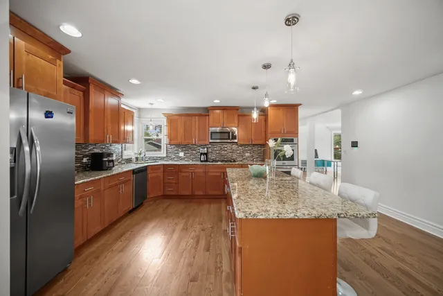 a large kitchen with stainless steel appliances granite countertop a large counter top a refrigerator and cabinets