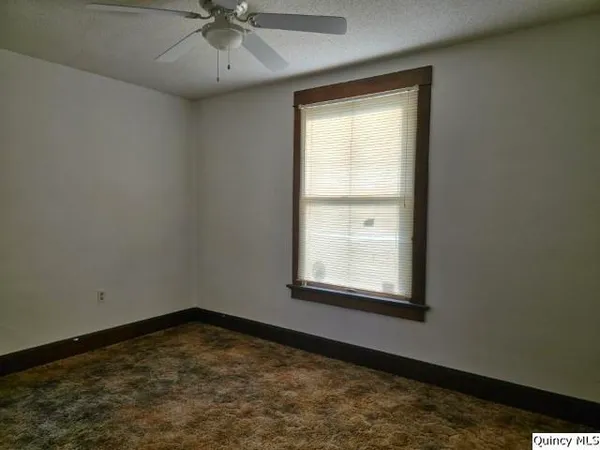 an empty room with a window and a fan