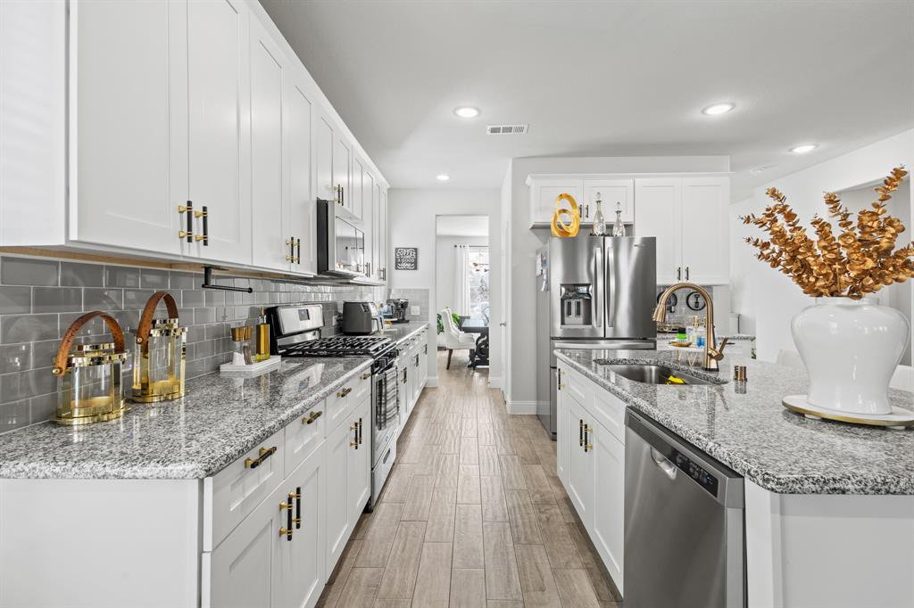 4220 Calla Drive Forney, TX 75126 - Photo 6 of 30 a kitchen with stainless steel appliances granite countertop a sink and stove top oven with wooden floor