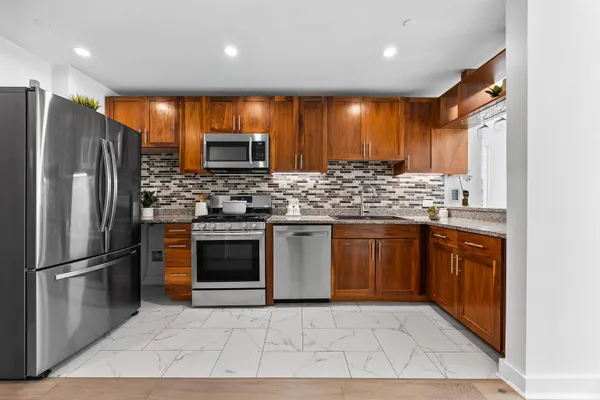 a kitchen with stainless steel appliances granite countertop a stove a sink and a refrigerator