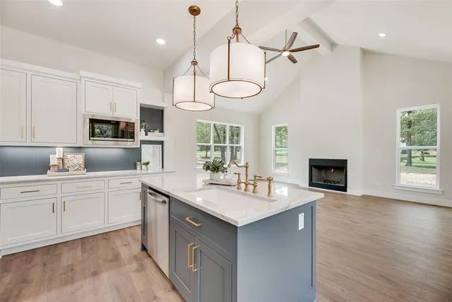 a kitchen with granite countertop a sink a counter space appliances and cabinets