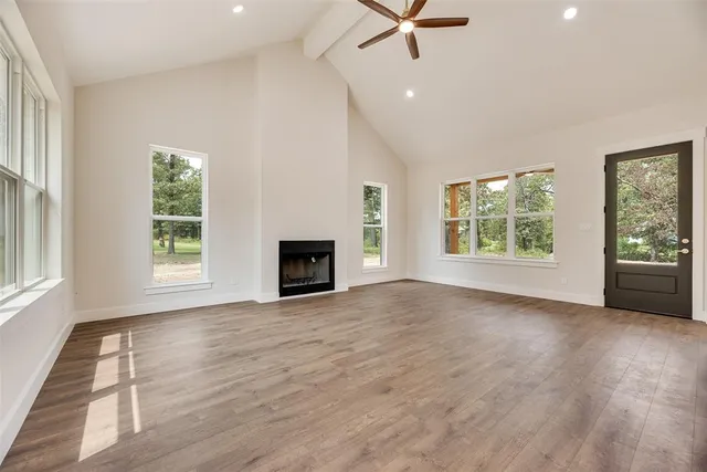 an empty room with windows fireplace and wooden floor