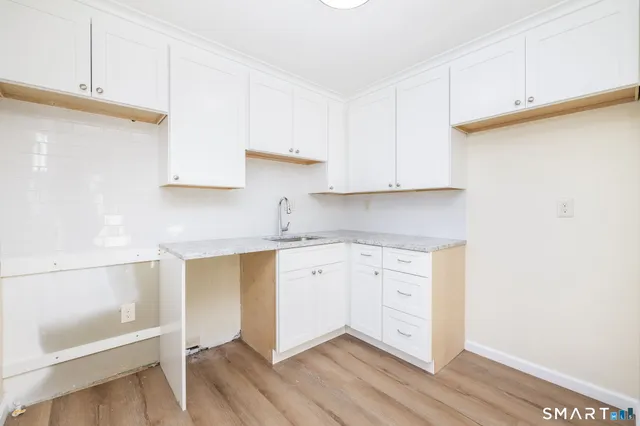 a kitchen with granite countertop white cabinets and a sink