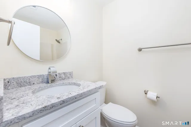 a bathroom with a granite countertop sink mirror vanity and toilet