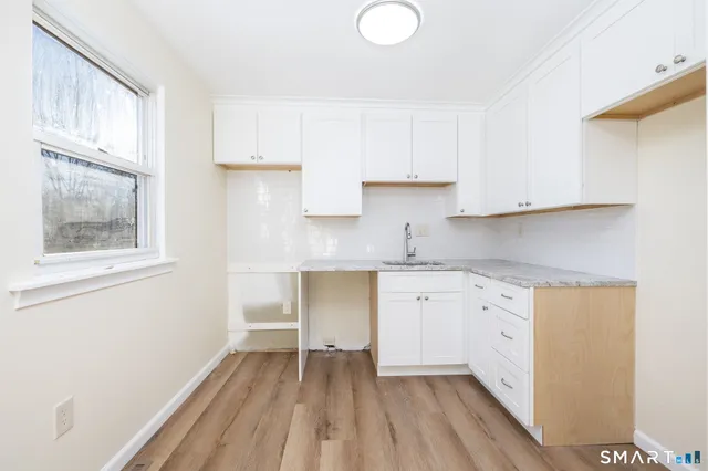 a kitchen with granite countertop white cabinets and a wooden floor