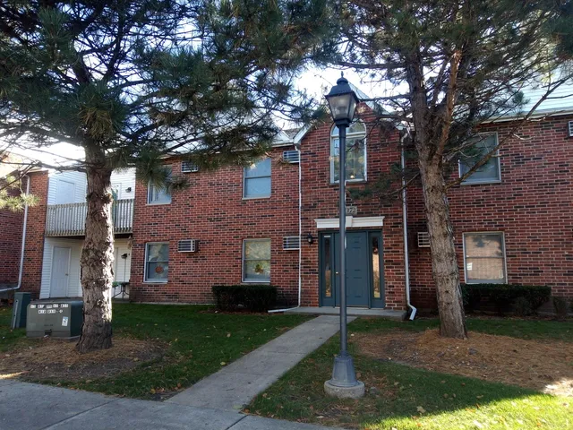 a front view of a house with a garden and tree