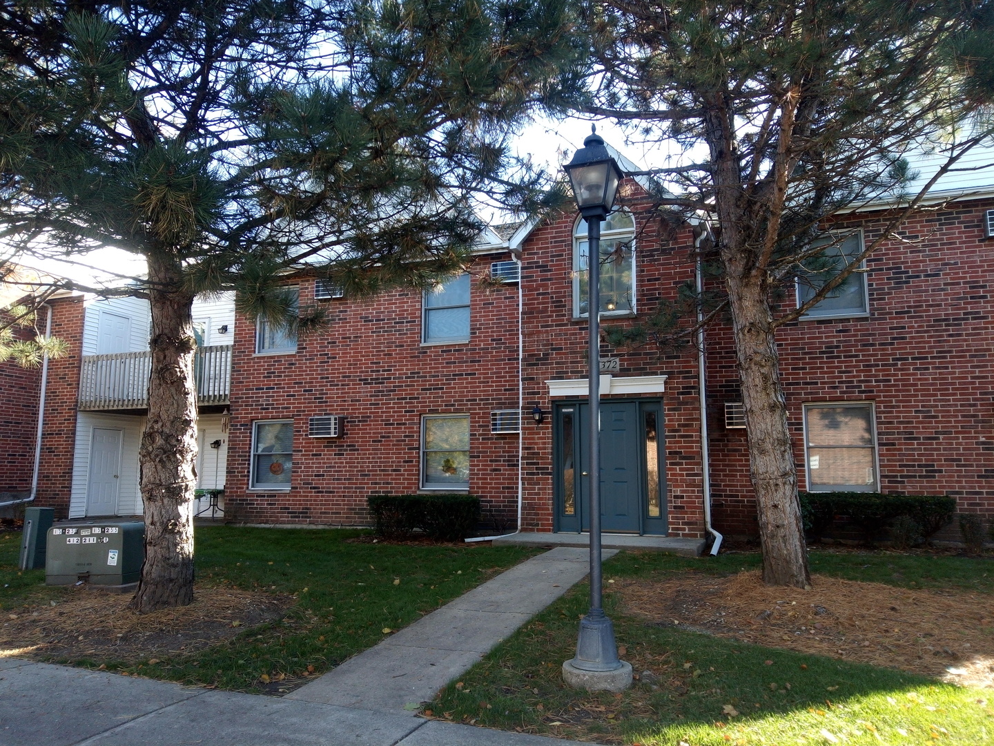 1372 Cunat Court, Unit 1B Lake In The Hills, IL 60156 - Photo 1 of 1 a front view of a house with a garden and tree