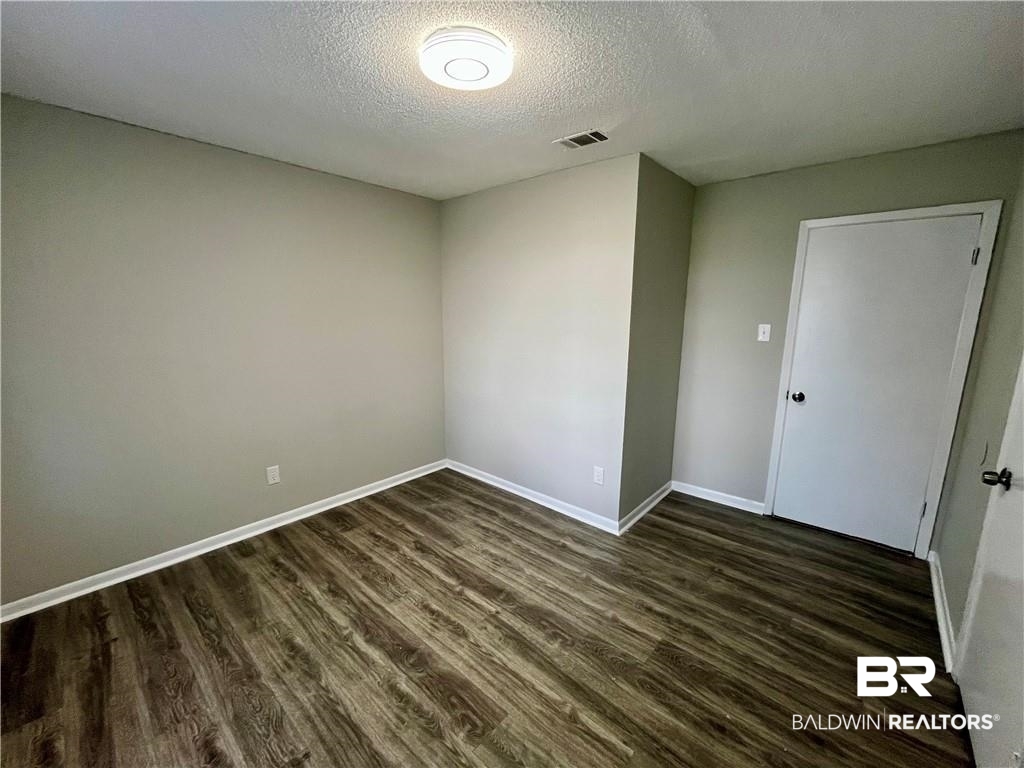 8636 Boe Road Irvington, AL 36544 - Photo 18 of 22 Unfurnished room with dark wood-type flooring and a textured ceiling