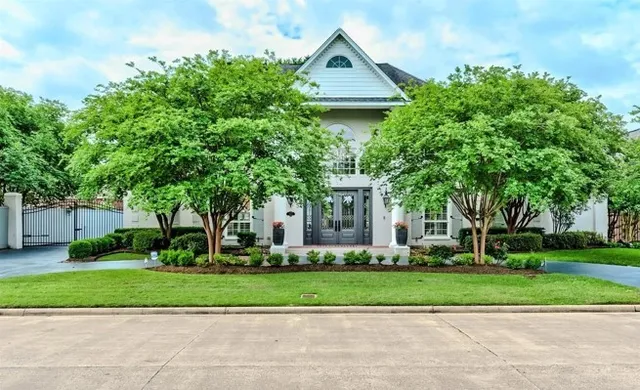 a view of a house with a yard and large trees