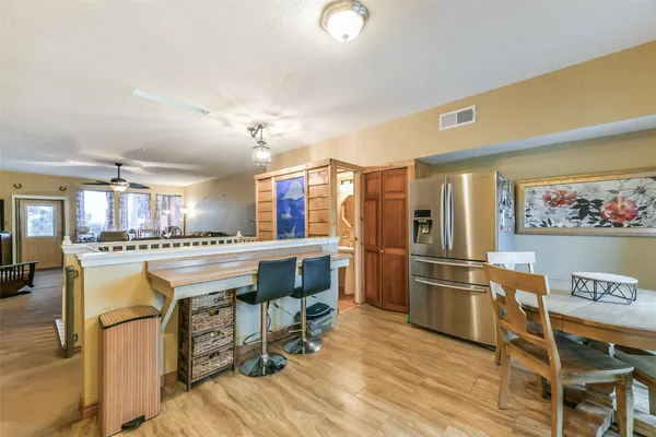 a kitchen with refrigerator a stove a dining table and chairs with wooden floor