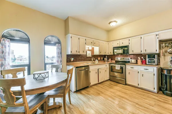 a kitchen with stainless steel appliances granite countertop a stove a sink dishwasher a dining table and chairs with wooden floor