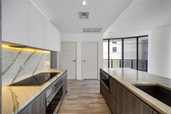 a large kitchen with granite countertop a sink and dishwasher a stove top oven with wooden floor