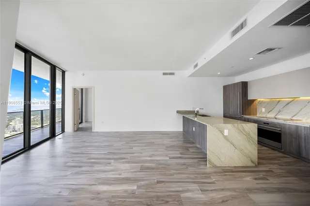 a view of kitchen with stainless steel appliances wooden floor and large window