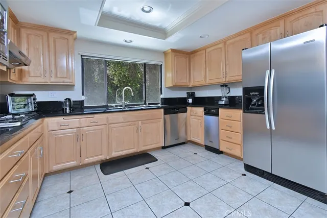 a kitchen with granite countertop a refrigerator sink and cabinets