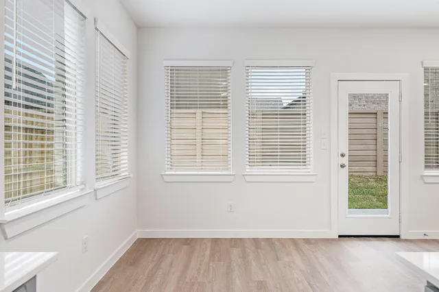 a view of an empty room with a window and wooden floor