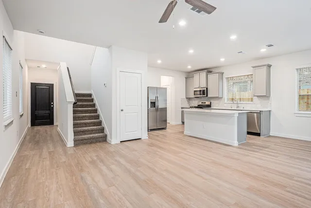 a white kitchen with granite countertop a stove top oven a sink and dishwasher