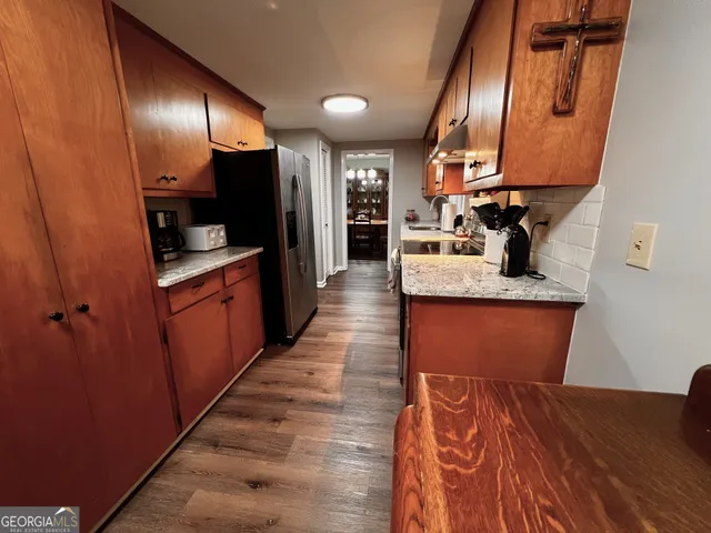 a kitchen with stainless steel appliances granite countertop a refrigerator a sink dishwasher and wooden cabinets with wooden floor