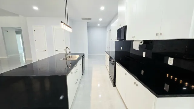 a large white kitchen with granite countertop a sink and dishwasher