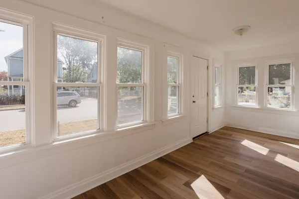 a view of an empty room with wooden floor and a window
