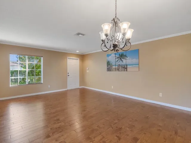 a view of a dining room with furniture a chandelier and wooden floor