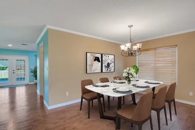 an empty room with wooden floor chandelier and windows