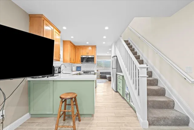 a view of a kitchen with kitchen island wooden floor and electronic appliances