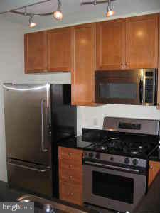 851 North Glebe Road, Unit 1013 Arlington, VA 22203 - Photo 3 of 6 a kitchen with granite countertop stainless steel appliances and wooden cabinets