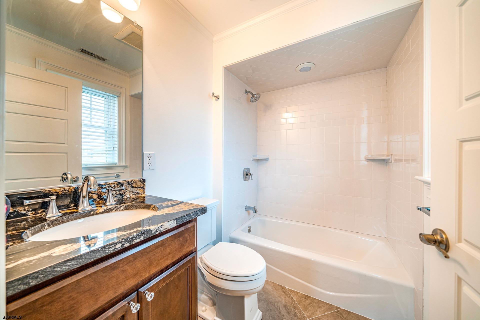 84 East Station Road Ocean City, NJ 08226 - Photo 20 of 30 a bathroom with a granite countertop toilet a sink and a bathtub