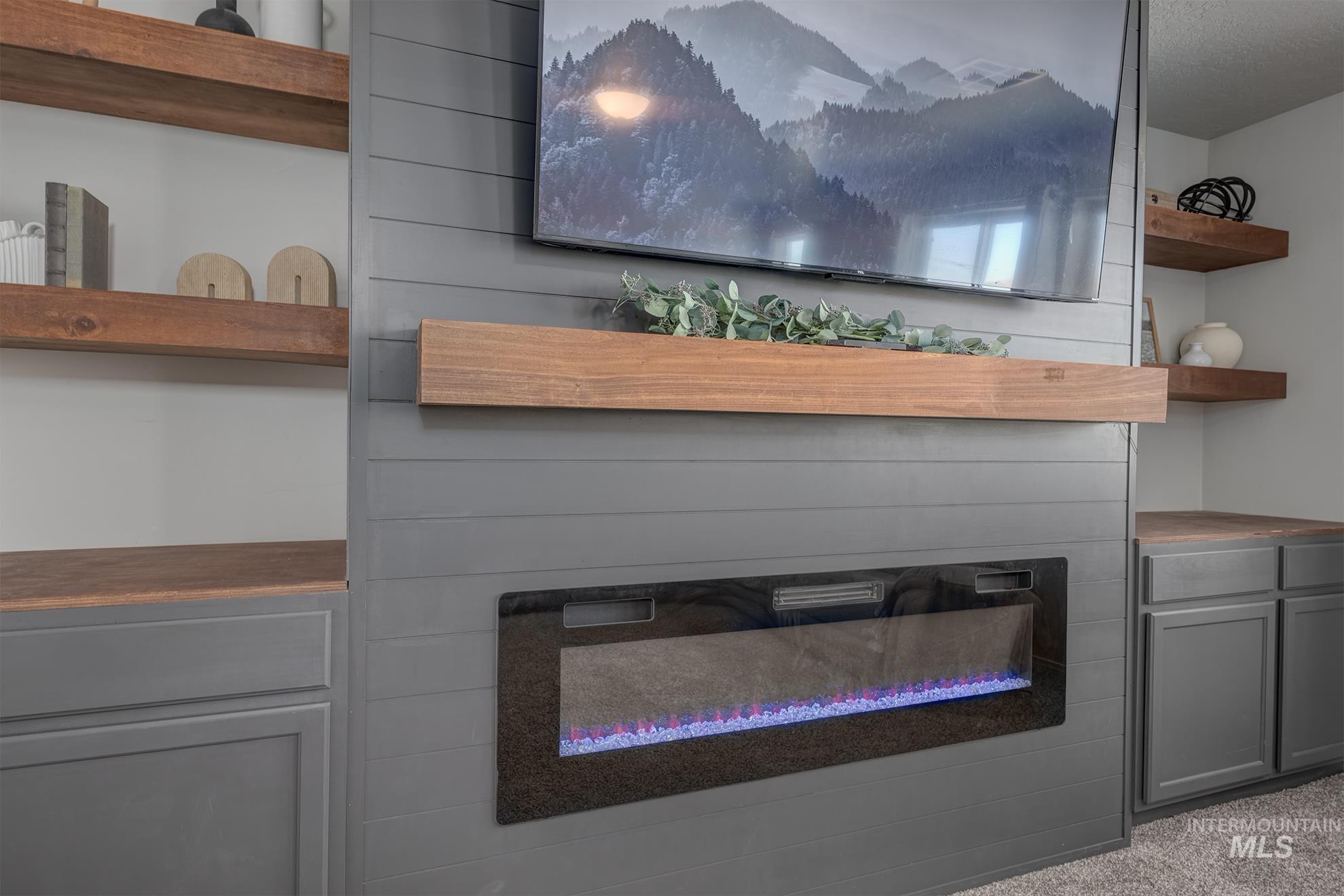 1049 Price Road Weiser, ID 83672 - Photo 22 of 47 Built-in entertainment wall featuring a mounted electric fireplace, wood-finish mantel, and shiplap paneling