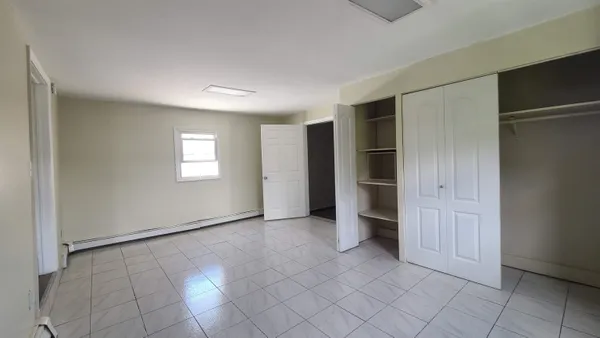 a view of an empty room with window and closet area