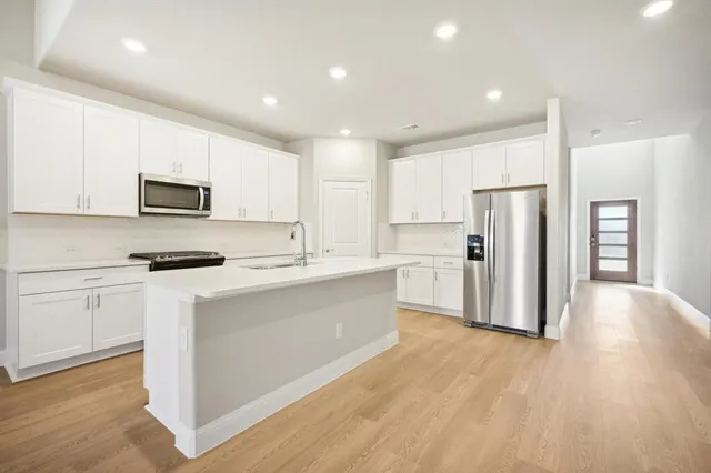 an empty room with wooden floor cabinet and windows