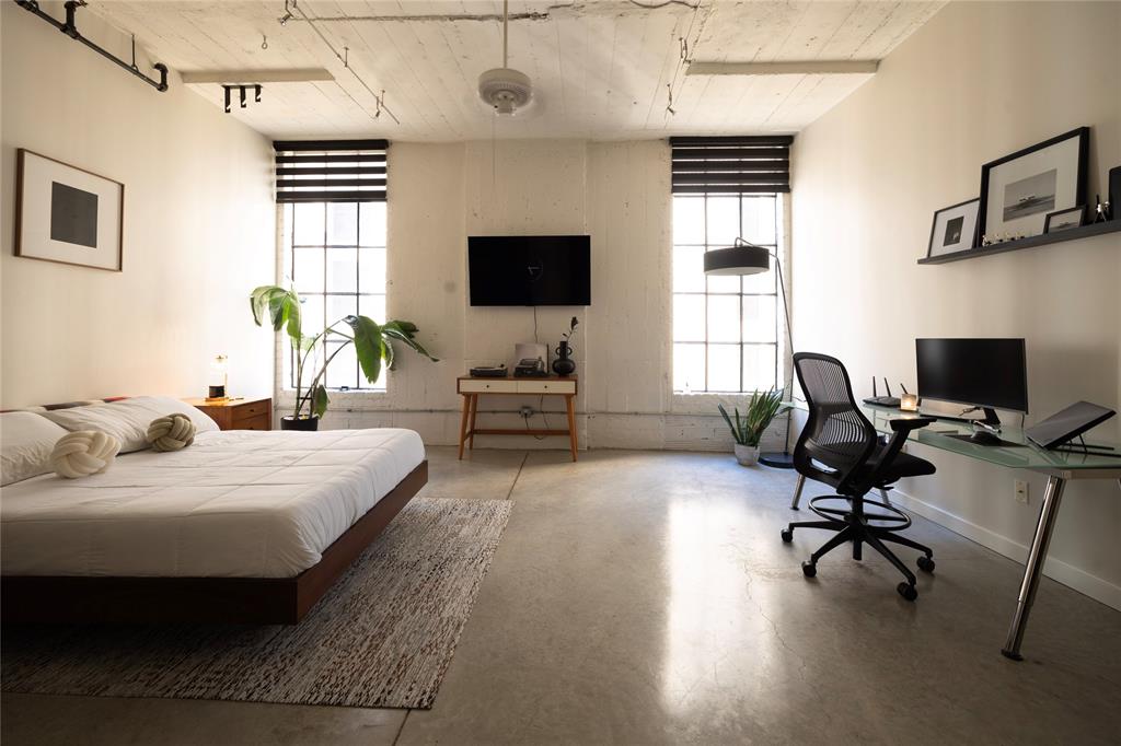 1122 Jackson Street, Unit 618 Dallas, TX 75202 - Photo 2 of 17 a bedroom with a bed a desk and chair with wooden floor