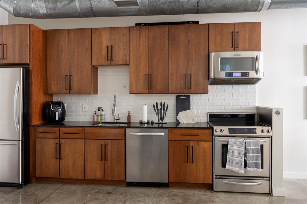 1122 Jackson Street, Unit 618 Dallas, TX 75202 - Photo 10 of 17 a kitchen with stainless steel appliances granite countertop a stove and a microwave
