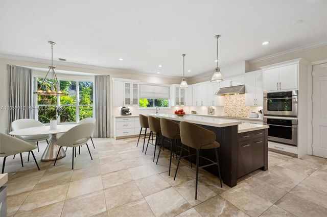 a kitchen with stainless steel appliances kitchen island granite countertop a table chairs and a refrigerator