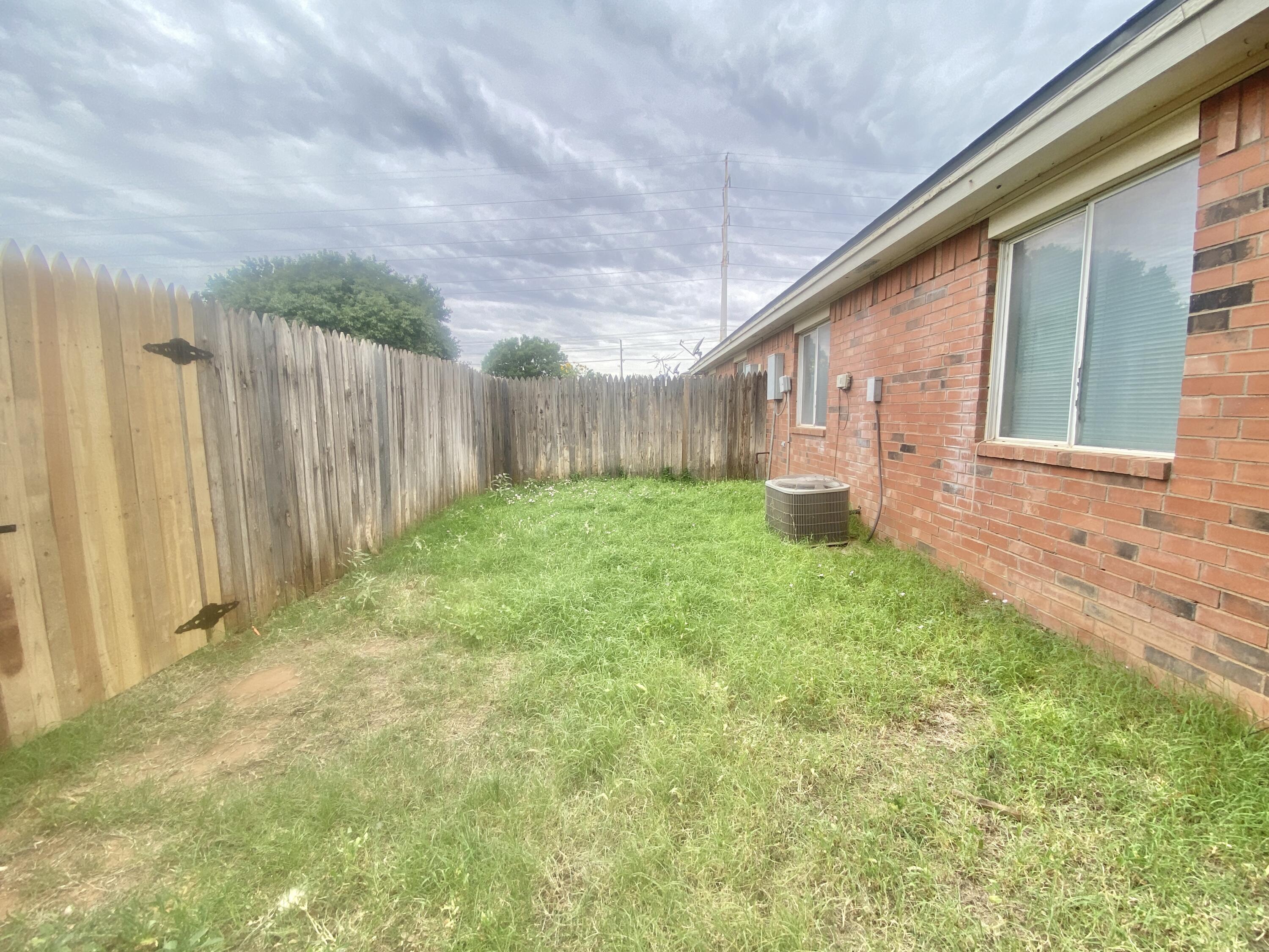 6320 7th Street Lubbock, TX 79416 - Photo 14 of 14 a backyard of a house with lots of green space and wooden fence
