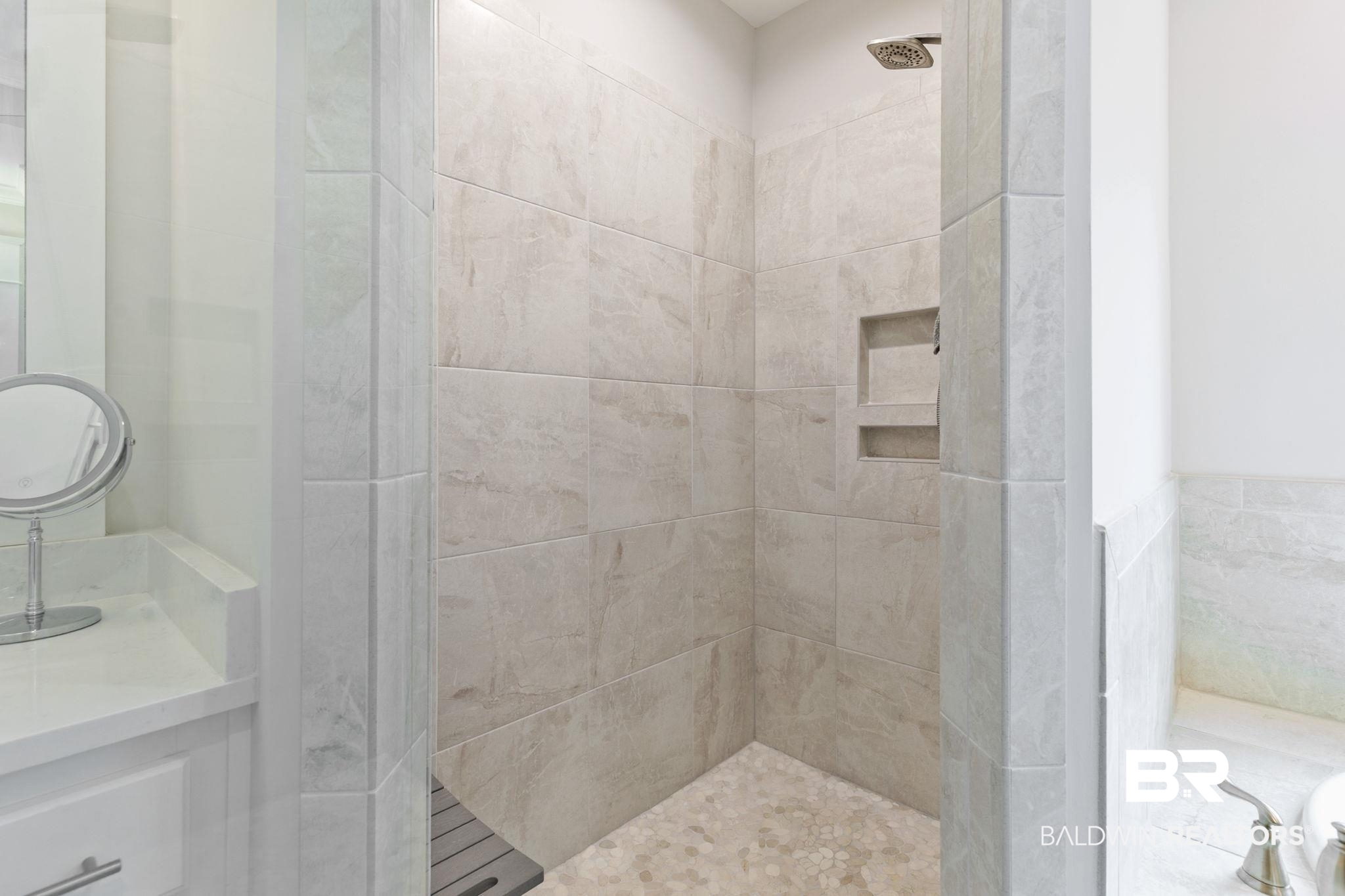 13233 Ibis Boulevard Daphne, AL 36527 - Photo 34 of 100 Walk-in shower featuring light-toned tile surrounds, a rain shower head, and an integrated tiled niche