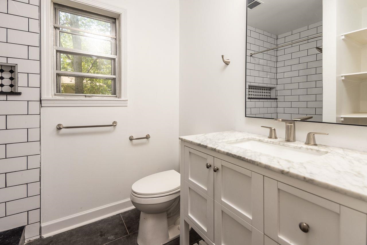 1243 Dearing Road Memphis, TN 38117 - Photo 14 of 25 a bathroom with a granite countertop toilet a sink and a window