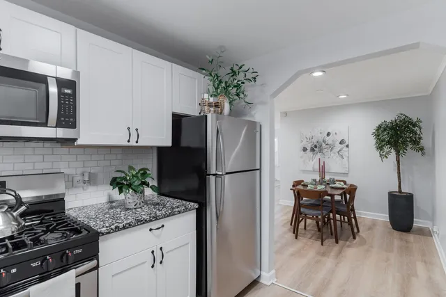 a kitchen with stainless steel appliances a refrigerator a stove a microwave a sink and chairs