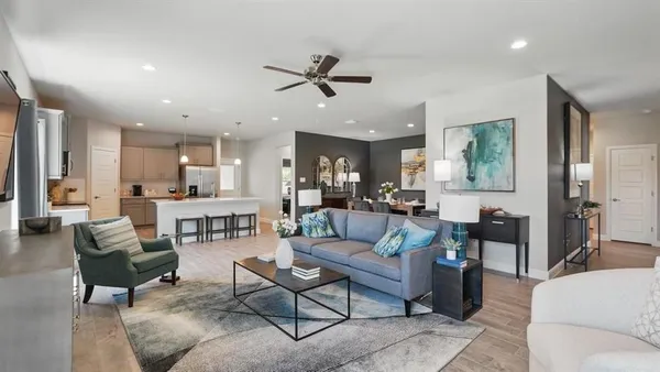a living room with furniture kitchen view and a wooden floor
