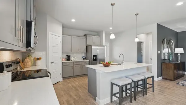 a kitchen with a sink a stove a refrigerator and white cabinets with wooden floor