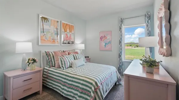 a bedroom with a bed and a lamp on dresser