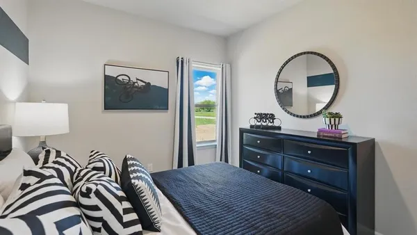 a bedroom with a bed and a mirror on dresser