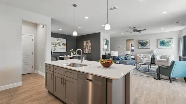 a large kitchen with a counter space a sink appliances and living room view